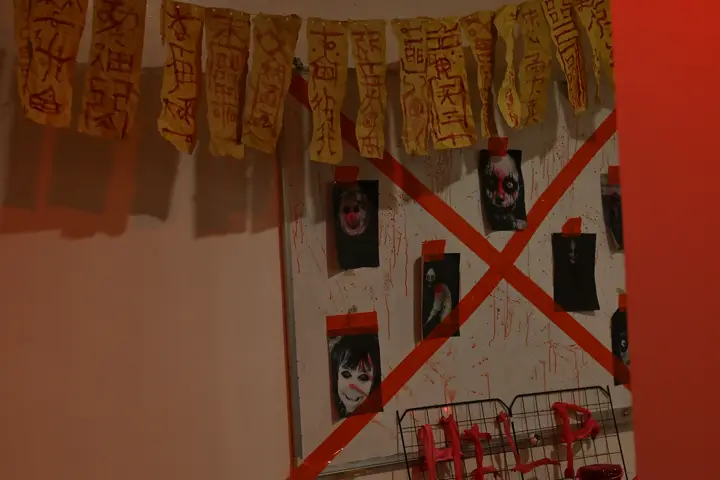 A wall of portraits crossed out with red tape under a paper garland