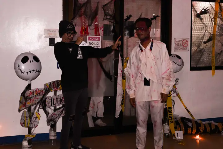 Teammate in a bloodied white coat posing by a decorated door