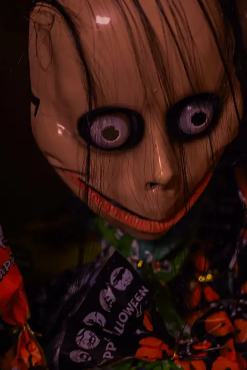 Creepy doll mask with wide staring eyes