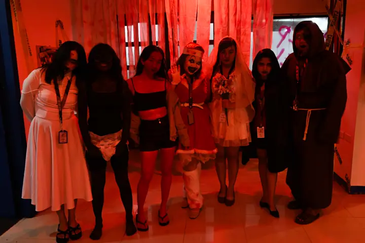 Seven teammates in matching horror costumes under red light